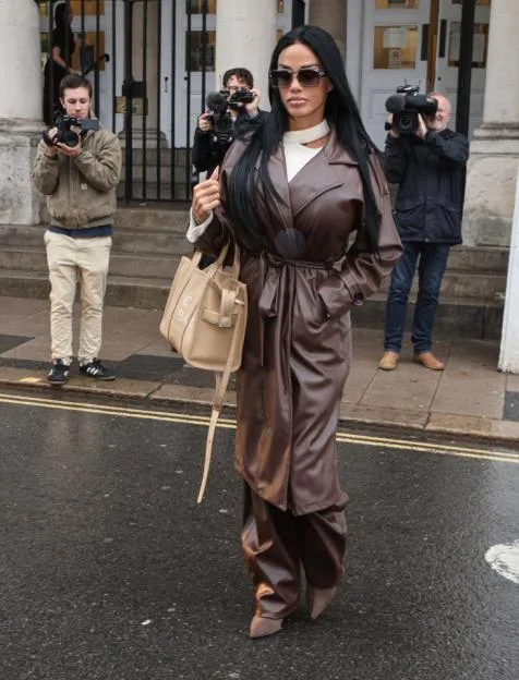 Katie Price wearing a brown leather trench coat and trousers leaves Lewes Crown Court, surrounded by photographers.