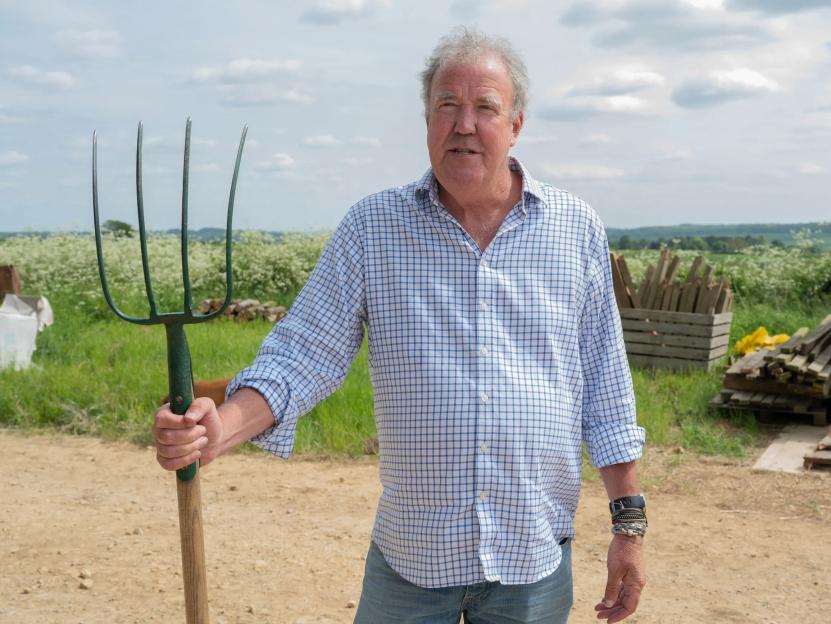a man in a plaid shirt is holding a pitchfork