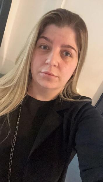 Sarah Wilson, a woman with long blonde hair, wearing a black shirt with a chain strap.