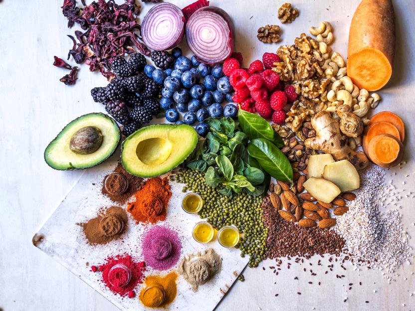 Multi colored vegetables, fruits, legumes, nuts and spices on wooden table