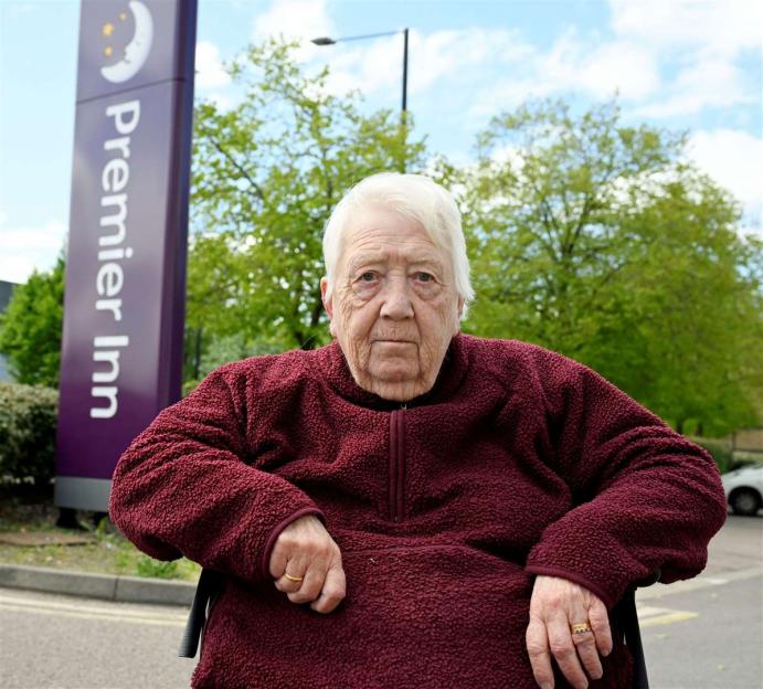 Jill Robson sitting outside a Premier Inn hotel.