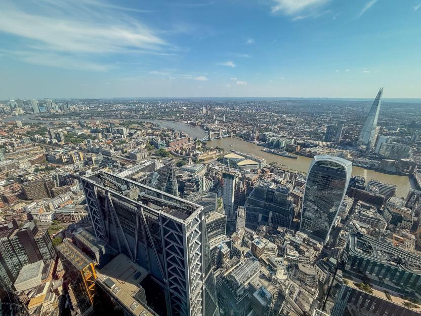 Panoramic view of London from above, with the River Thames, Tower Bridge, and The Shard visible.