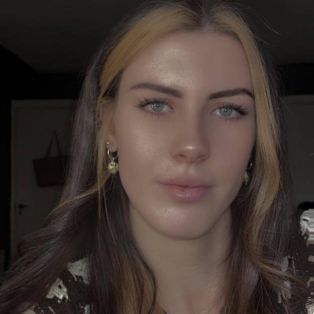 A woman with brown hair and light blonde streaks looking directly at the camera.