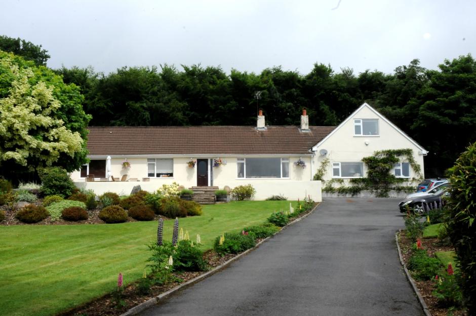Ann Widdecombe's home, a cream-colored house with a brown roof and a large garden.