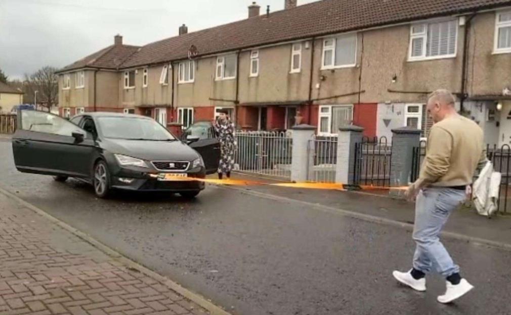 A man pulling a black car with a rope attached to his penis.