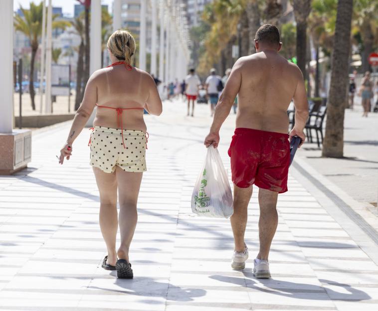 A couple walks down a sunny path in Benidorm, Spain.