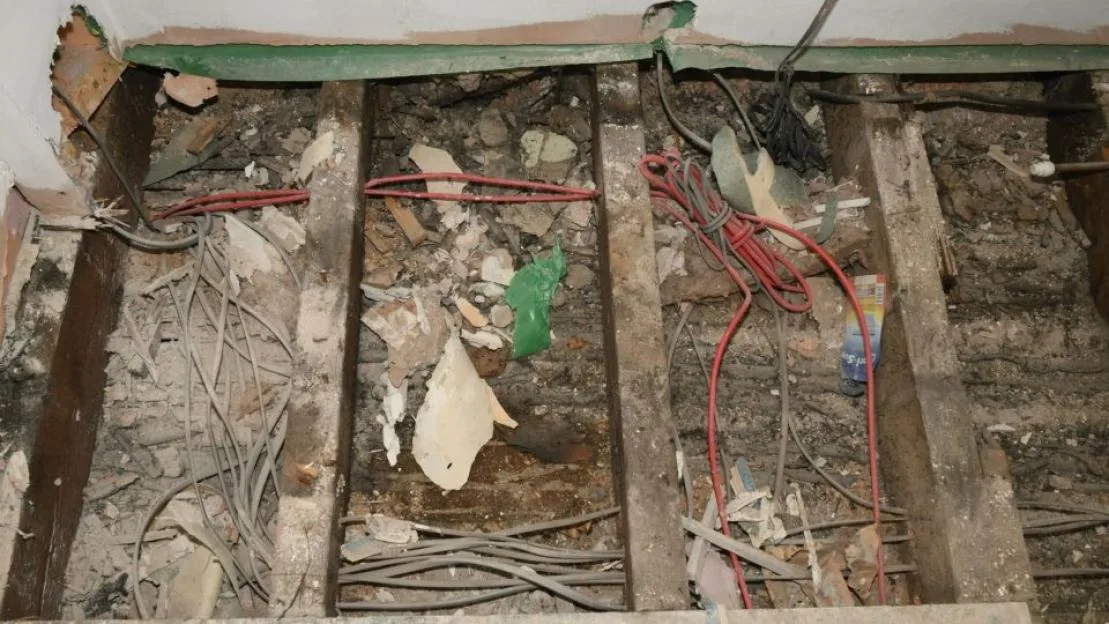 Debris and wiring under floorboards of a home being renovated.