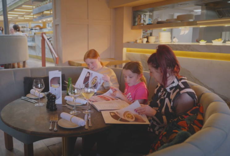 A mother and her two daughters looking at menus in a restaurant.