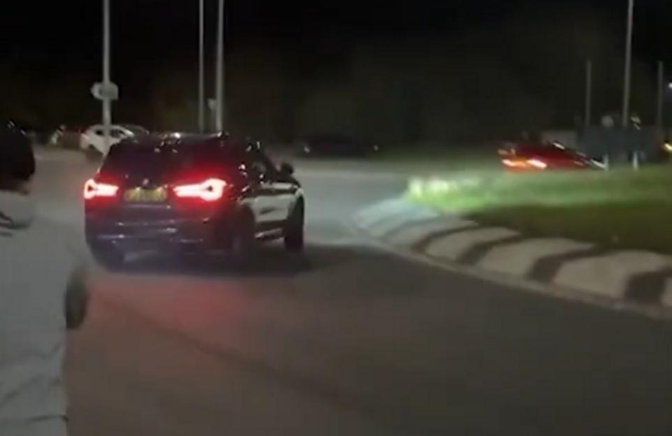 Connor Charlton drifting a black BMW X3M Competition around a roundabout at night.