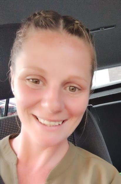 A woman with braided hair and an olive-green shirt smiles at the camera.
