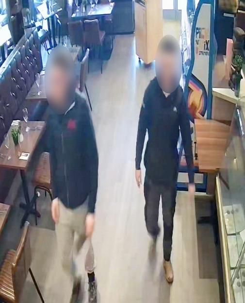 Surveillance footage of two men, faces blurred, walking through a restaurant.