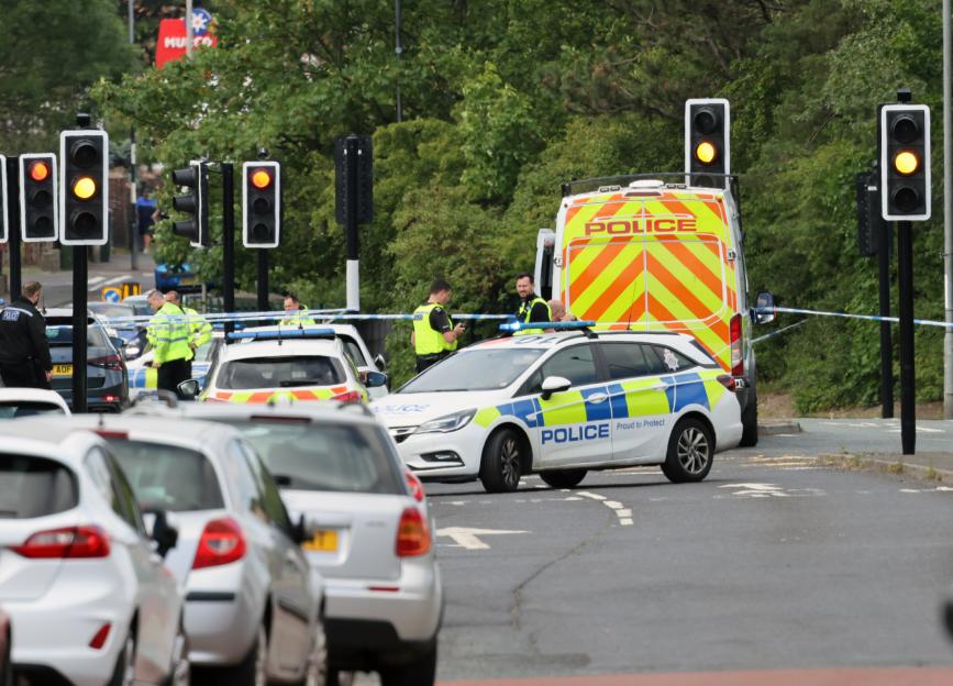 Police cars and officers responding to an emergency on a road with traffic lights.
