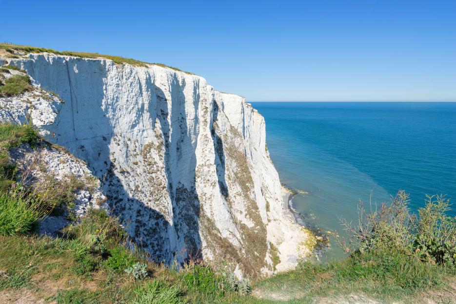 The White Cliffs of Dover overlooking the English Channel under a clear blue sky.