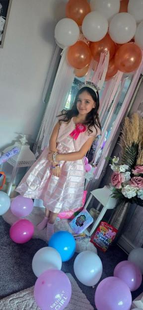 Aria Thorpe on her birthday, wearing a pink dress and a "Happy Birthday" tiara, surrounded by balloons.