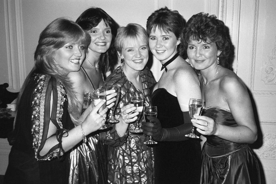 Black and white photo of The Nolans pop group, Linda, Anne, Bernie, Coleen, and Maureen Nolan, posing with drinks.