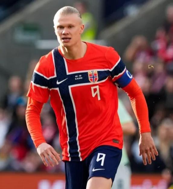 Erling Haaland in his Norway national team kit on a soccer field.