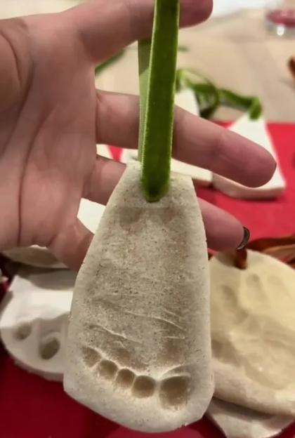 Salt dough ornament with a child's footprint impression and a green ribbon.