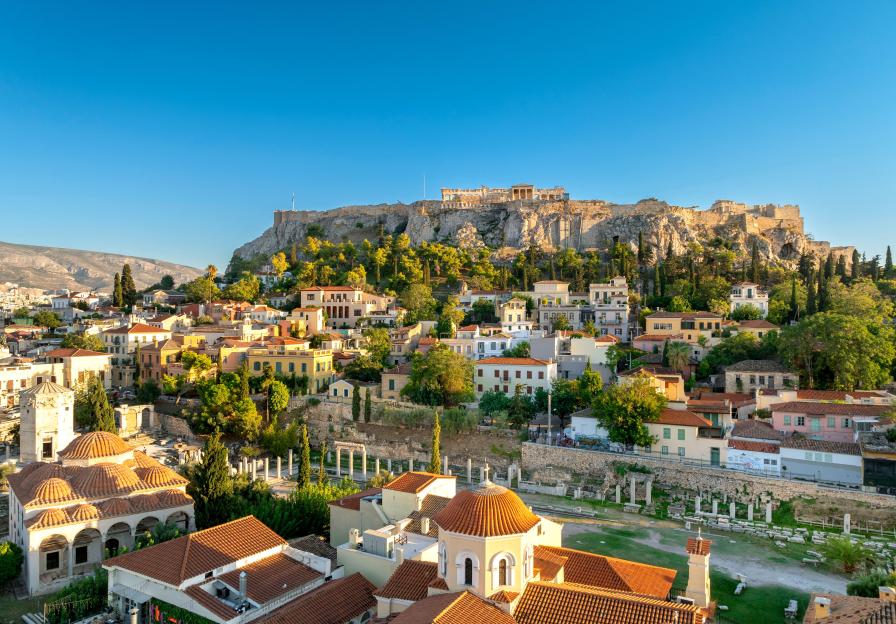 Panoramic view of Plaka and the Acropolis in Athens, Greece, with buildings and trees in the foreground.