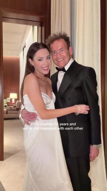 Lorna Lux and her husband embrace, with text reading "POV: married 16 years and we're still obsessed with each other".