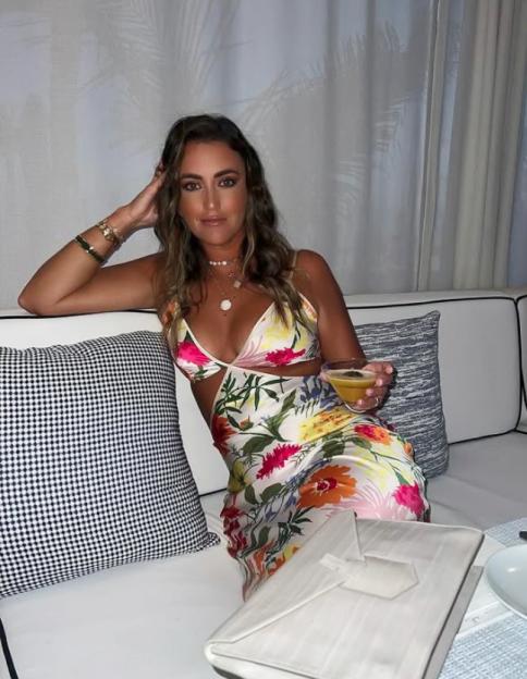 Georgina Leigh Cantwell in a floral dress, holding a drink.
