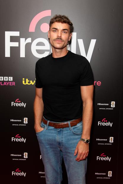 Harry Cooksley stands in front of a Freely branded background at the "Freely Fandom House Party."