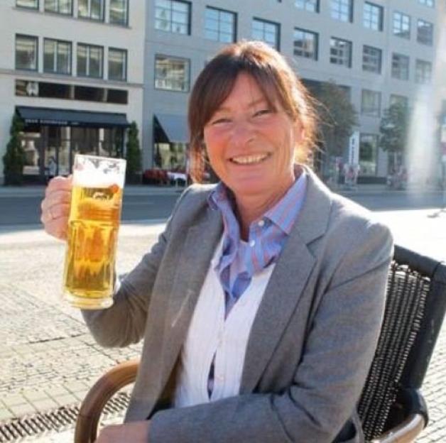 Sandra Thomas holding a large glass of beer.