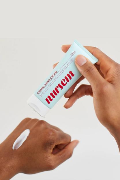 A hand squeezing Nursem Caring Hand Cream onto the back of another hand.