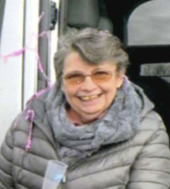 Josephine Rule, a 73-year-old grandmother, smiling while wearing a gray puffer jacket and gray scarf.
