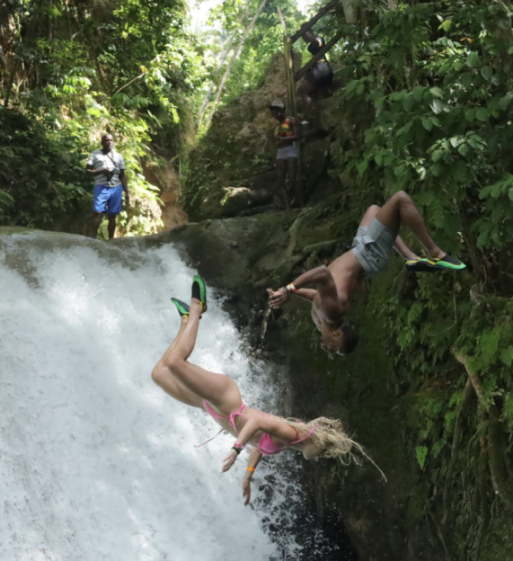Two people jumping off a waterfall.