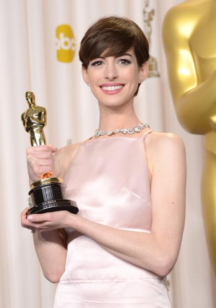 Anne Hathaway posing with her Oscar award.
