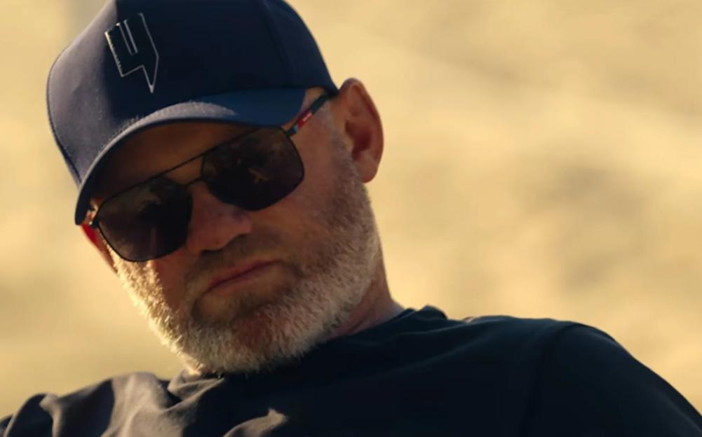 Wayne Rooney, wearing a cap and sunglasses, in a close-up shot.