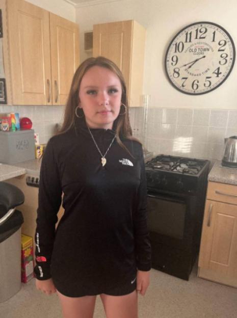 A 12-year-old girl named Brooke Wiggins in a black long-sleeved shirt standing in a kitchen.