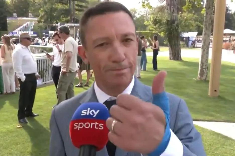 A man in a suit giving a thumbs up with a blue cast on his hand, holding a Sky Sports microphone.