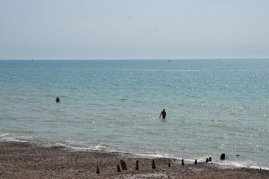 Two nude people swim in the sea.