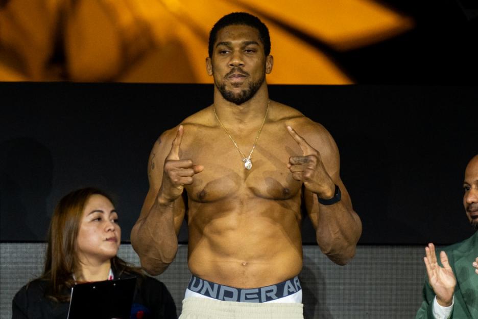 Anthony Joshua shirtless, pointing fingers at a weigh-in.