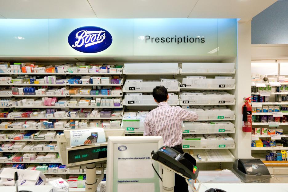 Pharmacy counter; UK Pharmacy interior; Boots the Chemist, the pharmacist working in the pharmacy, UK. Uk worker example.