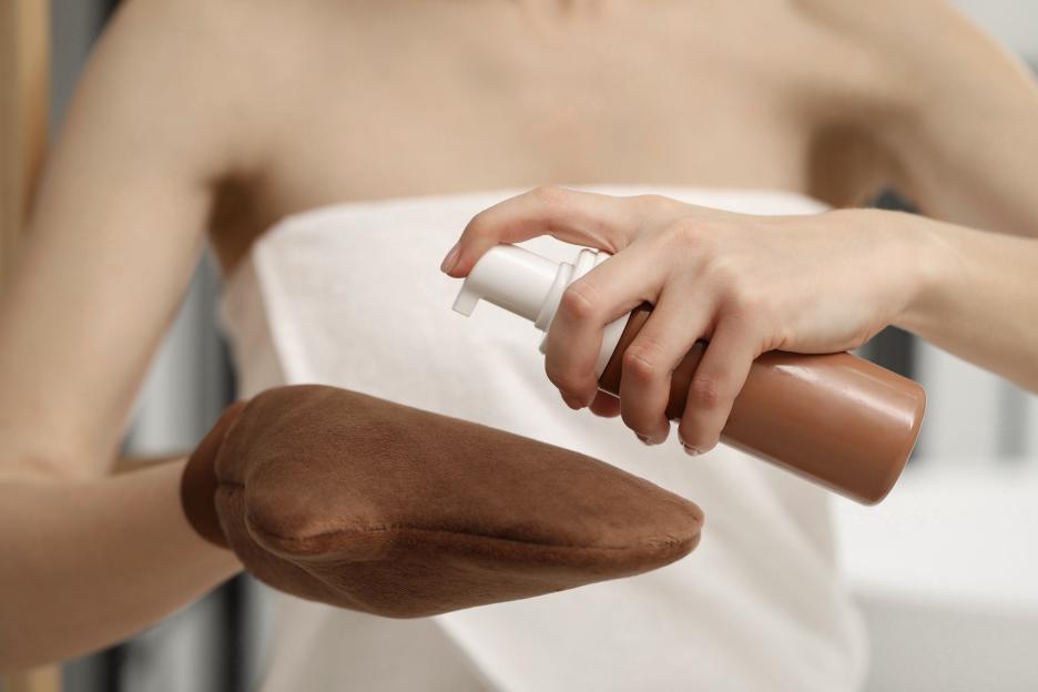 Woman applying self-tanner to a tanning mitt.