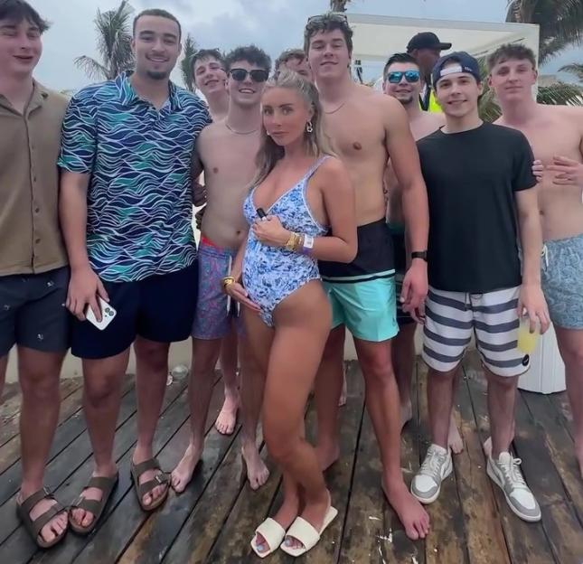 Bonnie Blue and a group of young men standing together, with Bonnie Blue holding her stomach.