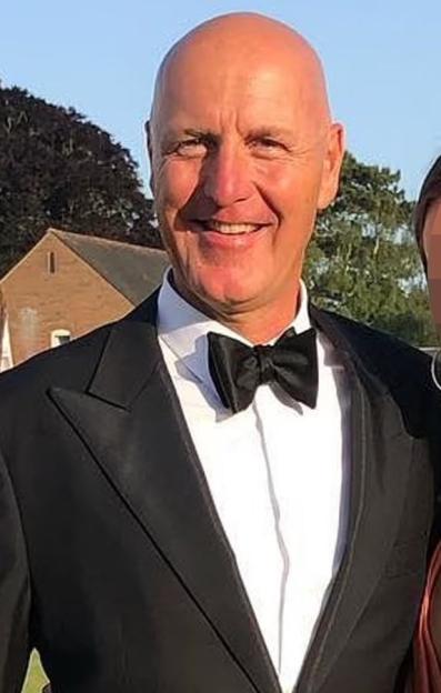 Graham King, a bald man with a black bowtie, smiling.