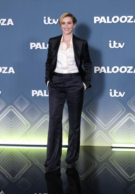 Vicky McClure smiling while wearing a black Adidas tracksuit and white sneakers.