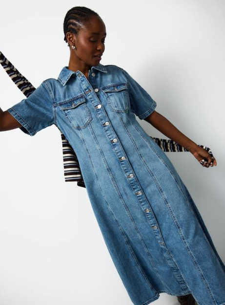 A woman in a light blue denim midi dress with short sleeves and buttons down the front, against a white background.