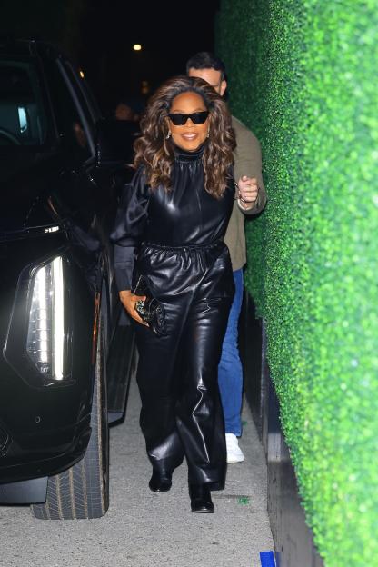 Oprah Winfrey arriving in a sleek all-black leather ensemble, matching shades, and a jeweled clutch.