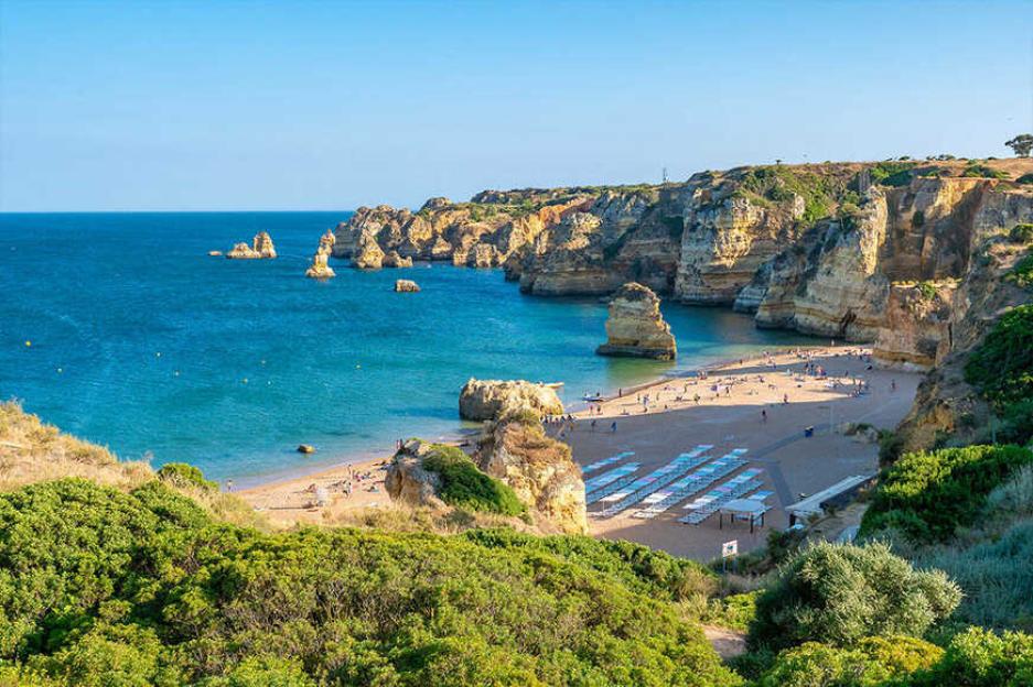 Coastal cove beach with blue water, sandy shores, and rock formations.