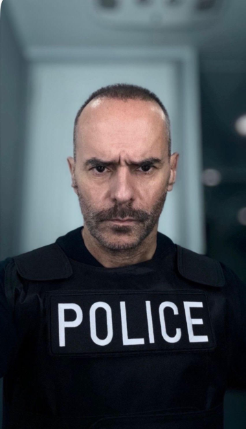 Michael Greco in "Fightland" wearing a police vest with a stern expression.