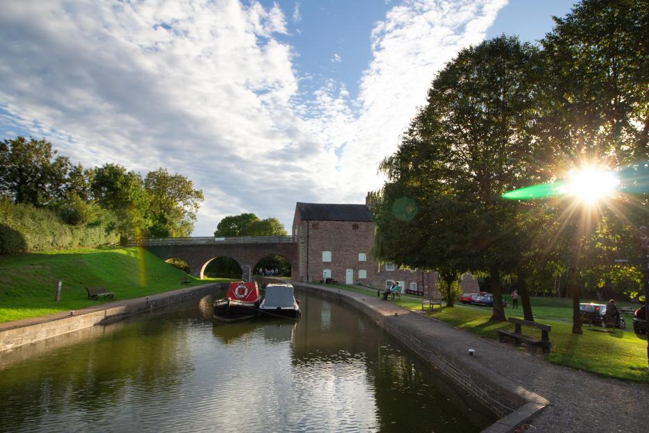 Late evening scene of Moira Furnace and the Ashby-de-la-Zouch Canal, with moored canal boats and a setting sun.