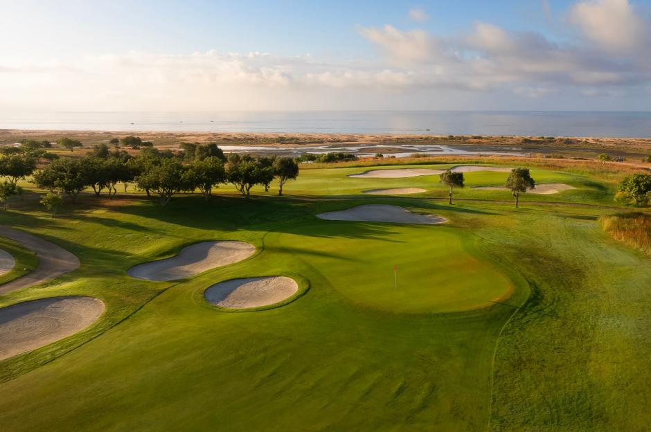 Quinta da Ria golf course with green fairways, sand traps, and the ocean in the background.