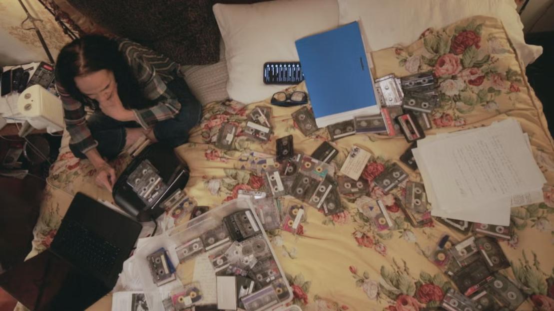 Laura Greenberg surrounded by audio cassette tapes and papers related to her research.