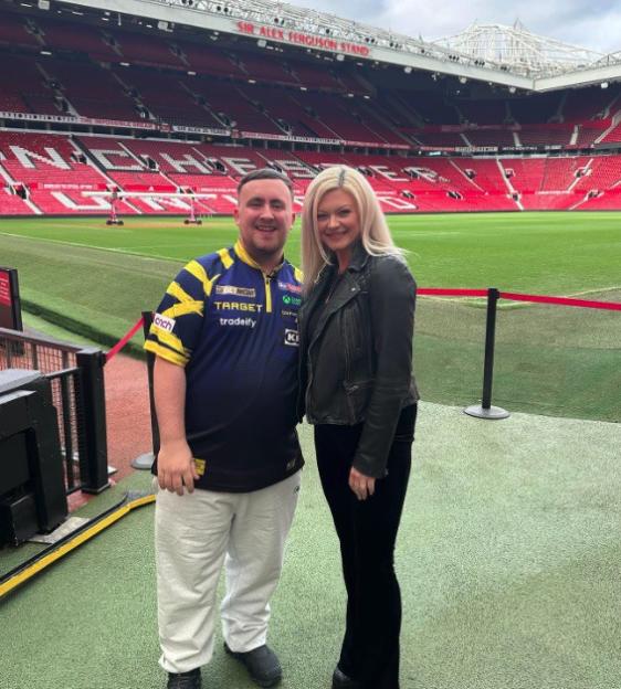 A man and woman standing on the field of a large stadium.