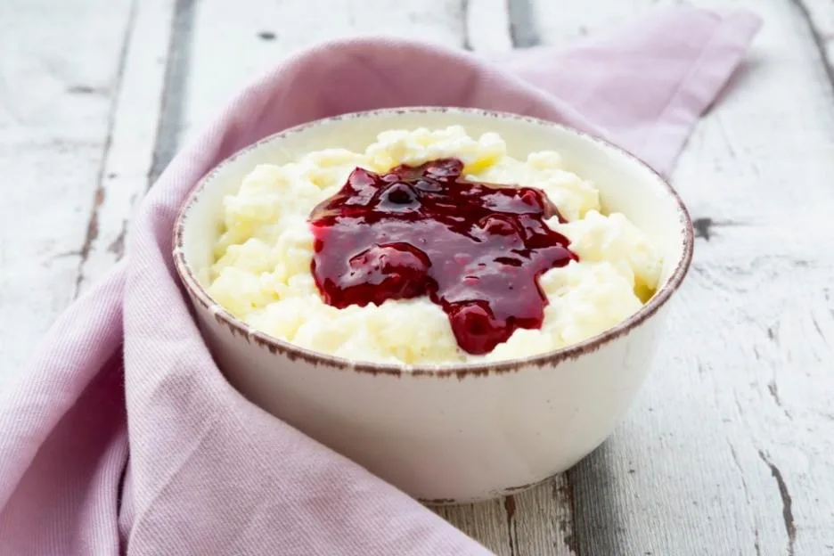Bowl of rice pudding topped with cherry and berry groats.