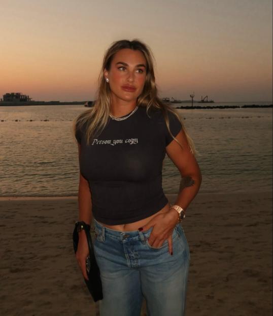 Aryna Sabalenka standing on a beach at sunset.